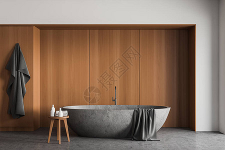 现代洗手间内部有白色和木墙水泥地板舒适的石浴缸和带毛巾和美容制品图片