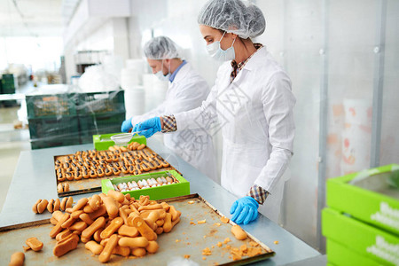 装白色大衣的糖果工厂人站着准备美味的糕点背景图片