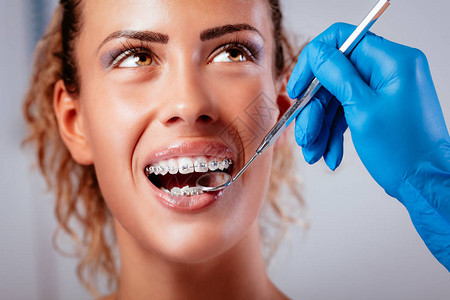 在年轻微笑的女病人身上戴牙镜检查牙图片
