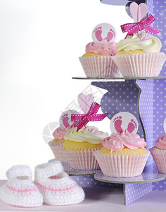 紫色圆点纸杯蛋糕摊上的粉红主题女婴蛋糕和靴子与白色背景的婴儿淋浴或新生育婴图片