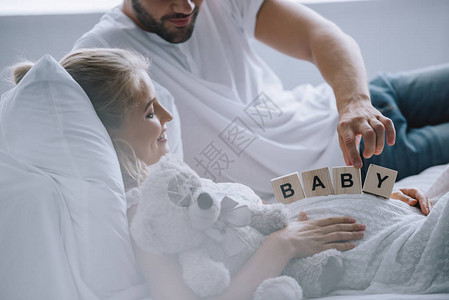 男子在家中用泰迪熊的怀孕妻子肚上放置木砖块和婴儿字图片