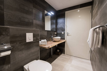 现代浴室铺有白色和灰色瓷砖有一个带配件的白色水槽大镜子毛巾架马桶带毛巾的白色支架和一图片