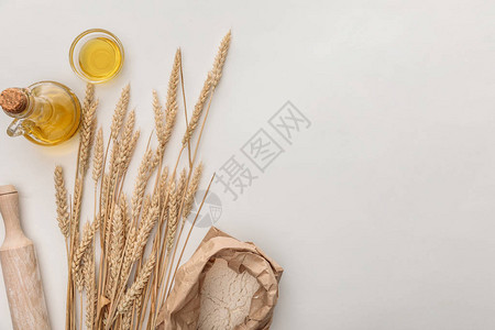 白色表面小麦钉滚针橄榄油和面粉背景图片