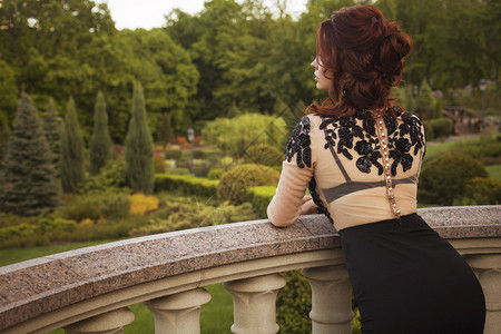 美丽感的黑发美女奢华富豪女人站在花园附近的阳台上穿图片