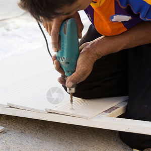 木匠手在建筑工地用电钻在木头上图片