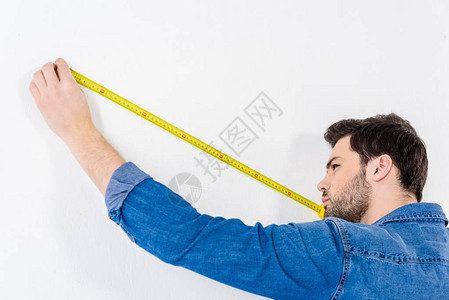 用白色卷尺测量墙的人图片
