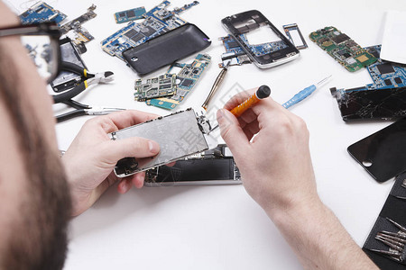 修理工用螺丝刀拆卸智能手机修理坏电话的技术员电子维修服务修理工pov图片