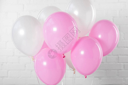 白色砖墙背景上的粉色和白色派对气球图片