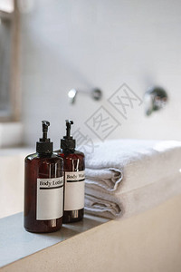垂直照片和近视两瓶天然化妆品护身在白陶瓷浴缸顶上在明亮的浴室里用模糊的背图片