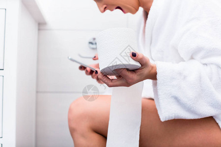 坐在马桶上的女人拿着卫生纸在浴室的智能图片