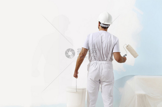 画家人在用油漆滚筒和水桶工作壁画概念图片