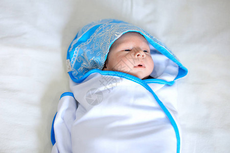 新生婴儿的肖像裹着蓝色边缘的白色毯子图片
