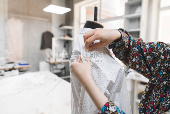 时装设计师将针插入假人的衣服在工作室创作时尚服装年轻的女裁缝图片
