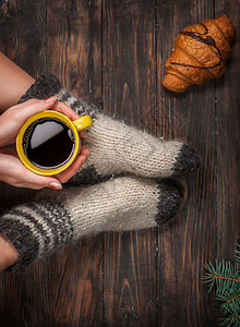 穿着暖和羊毛袜的女孩的腿和一杯咖啡升温图片