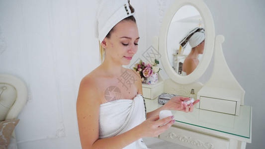 精致的女孩与美丽的护肤霜应用于面部和淋浴后的美容护理图片