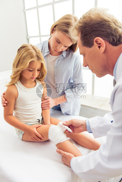 年轻中年儿科医生给小女孩的膝盖贴了绷带图片
