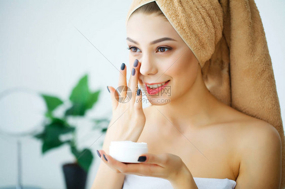 使用皮肤护理产品润湿剂或润滑剂以及照顾干肤色的美貌女图片