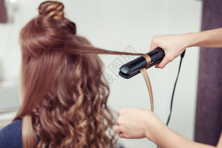 美发师用烫发器做发型的特写图片