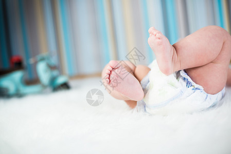 穿着尿布的新生婴儿的脚躺在毛绒毯子上图片
