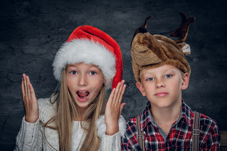 贴近女孩和可爱男孩的肖像在圣诞节帽子图片