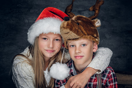 贴近女孩和可爱男孩的肖像在圣诞节帽子图片