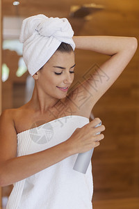 美丽的女人在淋浴后使用除臭剂图片