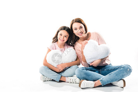 女儿和母亲坐在心形的枕头上看着图片