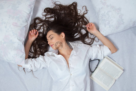 女孩睡在家里的一张白色床上年轻女子穿着睡衣在家里床上的白色床图片