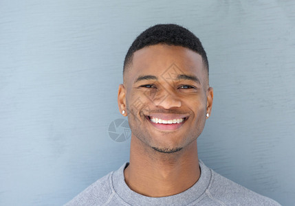 一位英俊年轻黑人男子在灰色背景上微笑图片