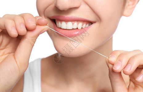 年轻女子在白色背景上用牙线清洁牙齿特写图片