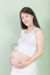 年轻漂亮的怀孕少女背着她的肚子在背景上背景图片