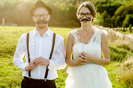 传统的年轻结婚夫妇新娘和Groom持有纸胡子准备婚礼图片