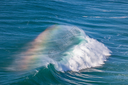巨型海洋浪潮与彩虹在喷雾中图片