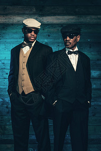 两个老式的非洲黑帮在旧木墙前穿着黑色墨镜图片