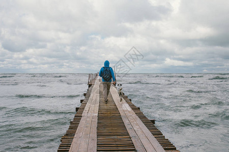 在波涛汹涌的大海背景下走在木码头上的人图片