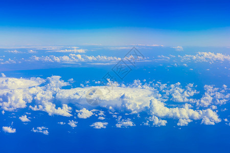 在蓝天空上从飞机窗口白云上方的天际和海洋图片