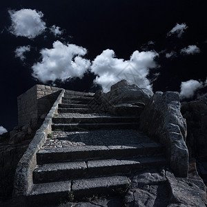 旧的花岗岩楼梯升起到黑暗的天空有白云和厚云图片
