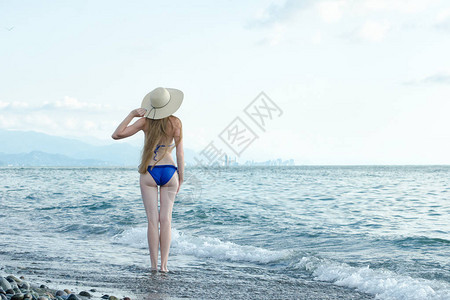穿着泳衣和帽子的女孩站在海图片
