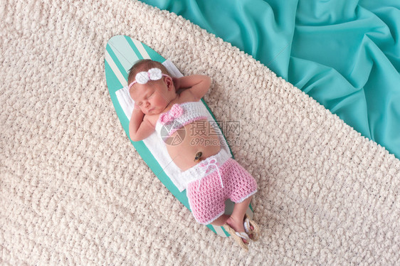 9天大的新生女婴睡在小冲浪板上图片
