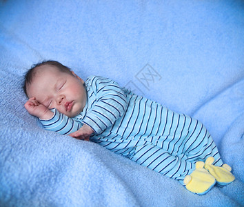 平静的婴儿睡在一条亮蓝毯子图片