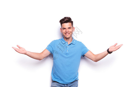 穿着牛仔裤和蓝色马球衫的英俊年轻男子的特写肖像张开双臂欢迎背景