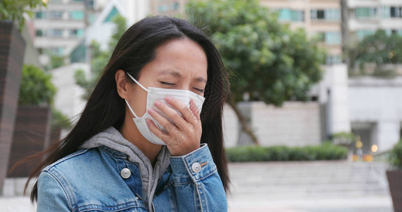 在户外戴口罩咳嗽的女人图片