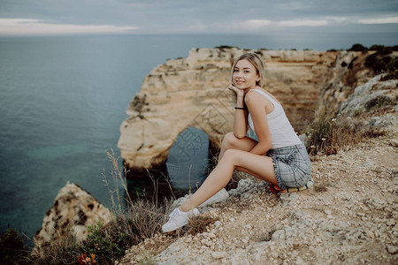 拉丁女孩坐在悬崖上享受葡萄牙大西洋附图片