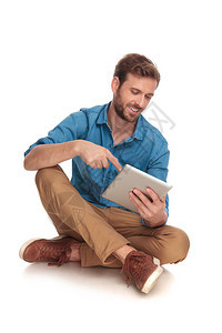 坐着笑坐的闲人触摸着平板电脑屏幕在白图片