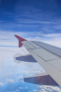 云和蓝天的喷气式飞机翼视图图片