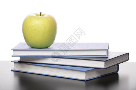 桌子上有三本书和苹果背景图片