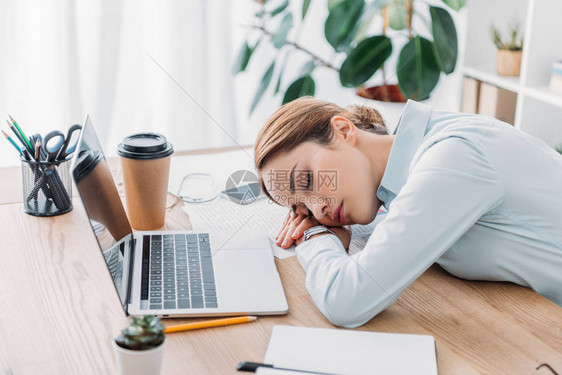 在现代办公室工作场所睡觉的劳动超负荷的成年图片