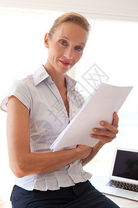 自信的高级女商人坐在办公桌上处理和阅读文书工作图片