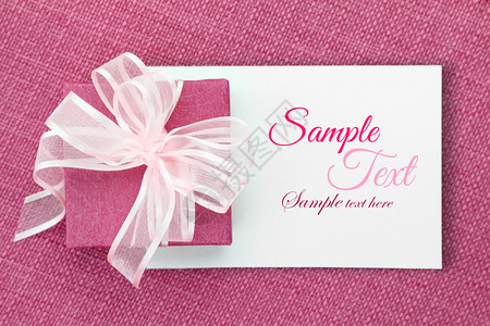 白色卡片上有丝带的粉红色礼盒图片