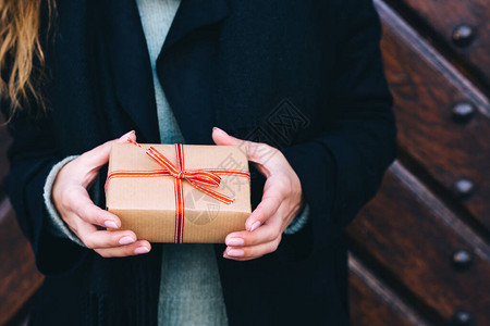 送圣诞礼物或生日礼物的女人包着棕色纸和红丝图片